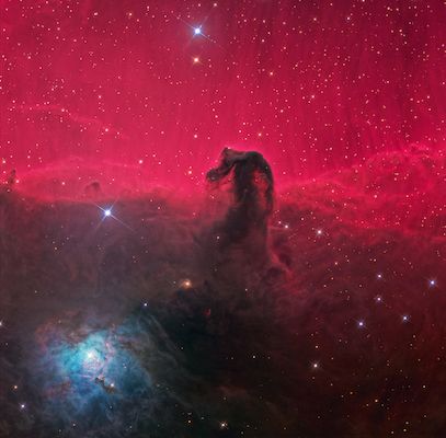 A lush red and black space photograph of a great nebula cloud surrounded by stars
