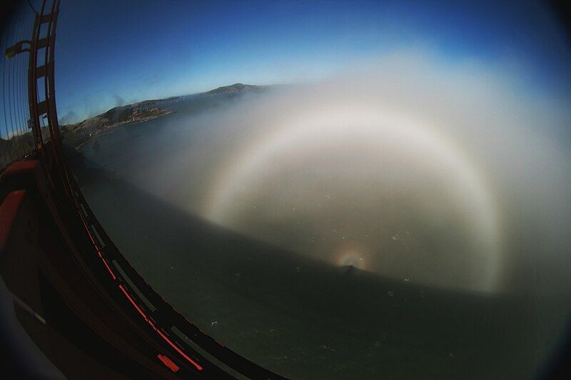 photo of a light phenomenon seen from a bridge, with several concentric rings of light and a tiny rainbow in the centre