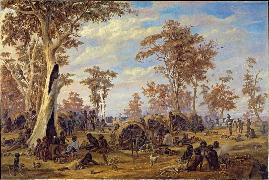 colonial-era painting of a large group of Aboriginal Australians camping in a lush golden field. They are sitting, lying, talking or eating food. Their camp shelters are woven from sticks and grass. Several dogs are hanging around and some horses can be seen in the background.