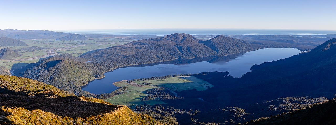 a still lake surrounded by huge wooded hills and sweeping plains.