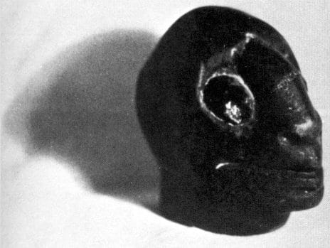 another grainy photo of a statuette. This one is a crude, black alien head with bulbous eyes. It looks a little like something you'd see on a conspiracy website about Roswell, or a production model built by H. R. Giger.