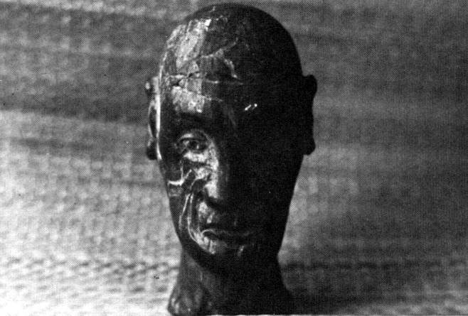 Grainy monochrome photo of an eerie, melancholy stone head