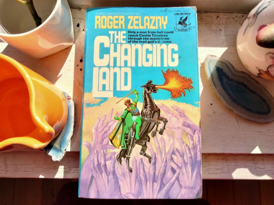 Photo of the novel. Cover art features a man on a robotic fire-breathing horse being attacked by giant purple hands.