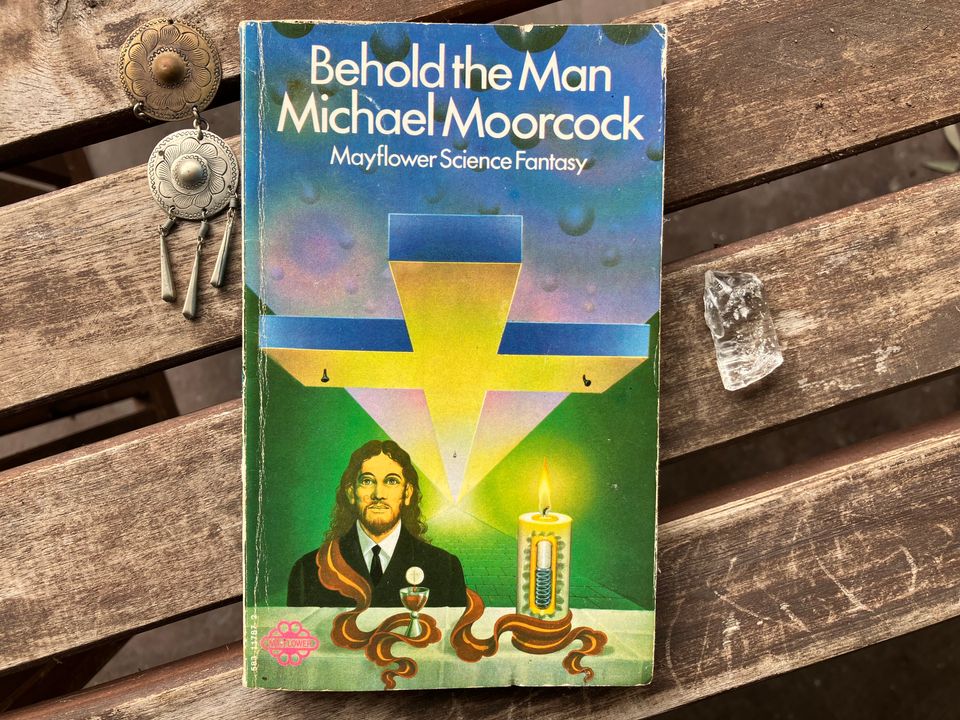 Book cover: a huge horizontal crucifix looms over a longhaired man, the Eucharist in front of him