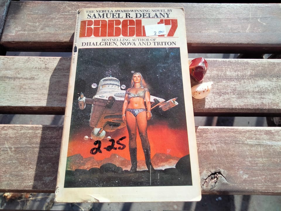 book cover depicting a woman in a silvery bikini, standing before a spaceship and a reddish alien sky